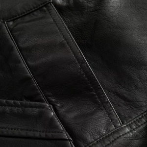 Detailed close-up of high-quality black leather texture and fine stitching on jacket