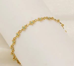 Close-up of a gold floral chain bracelet featuring blue turquoise center beads on white background