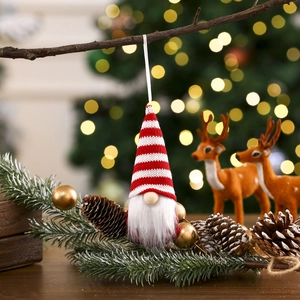 Detail of red and white knitted Christmas gnome ornament hanging on a festive tree branch
