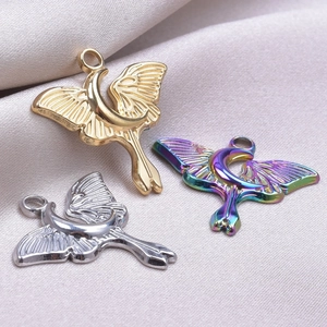 Detailed macro of 18k gold silver and aurora moon butterfly pendants on grey silk fabric