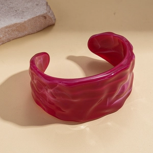 Macro detail of magenta marble acrylic cuff bracelet with irregular wavy edges