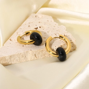 Detailed close-up of 18K gold hoop earrings with black stone charms on elegant fabric