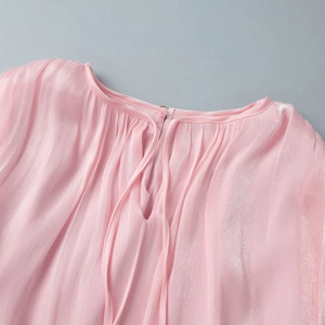 Detail showing pink pleated chiffon fabric texture with neckline keyhole and delicate tie
