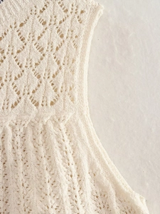 Dettaglio ravvicinato della trama e del motivo a maglia traforata del top color crema