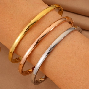 Close-up of minimalist curved titanium steel bangles in gold, silver and rose gold