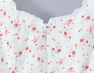 Detalle de vestido floral con ribete de encaje blanco y dos botones decorativos