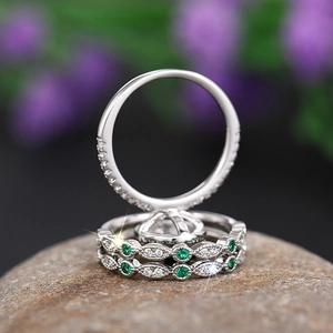 Macro detail of luxury three-piece ring set with green emerald gems on raw stone