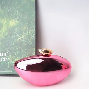 Macro detail of pink mirror acrylic evening clutch bag with elegant gold metal clasp