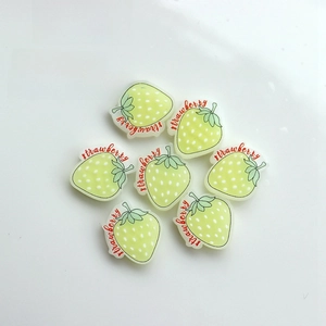 Close-up of a luminous light green strawberry resin DIY accessory with red lettering
