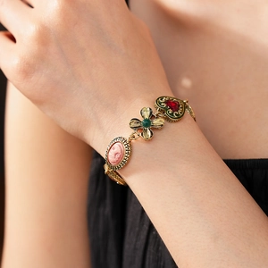 Gros plan du bracelet vintage doré avec camée rose et pierres colorées en forme de cœur