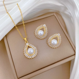 Detailed view of luxury gold teardrop pearl jewelry set on elegant white silk fabric