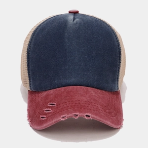 Detail of vintage trucker hat with navy denim crown and distressed red brim with mesh