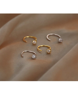Macro view of gold and silver C-shaped cubic zirconia earrings on premium silk