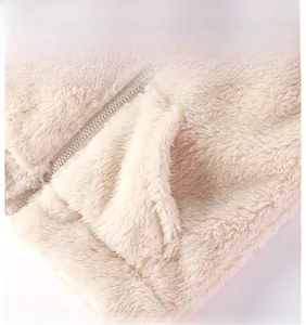 Dettaglio del gilet in peluche per neonati con trama in pile, cerniera e tasca a marsupio