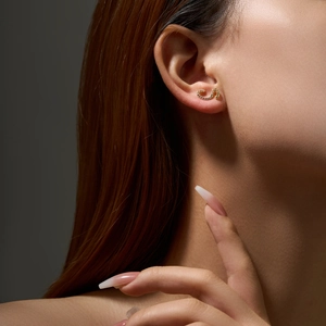 Close-up of a gold S925 silver hoop earring with cubic zirconia on a female ear