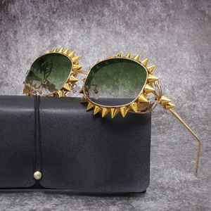 Nahaufnahme der goldenen Punk-Sonnenbrille mit Spikes und grünen Gläsern auf Etui
