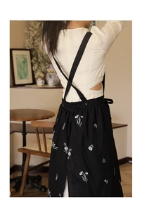Detail of black cotton linen apron showing exquisite floral embroidery and cross-back straps