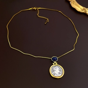 Detailed macro shot of vintage gold coin pendant necklace with a blue gemstone inlay