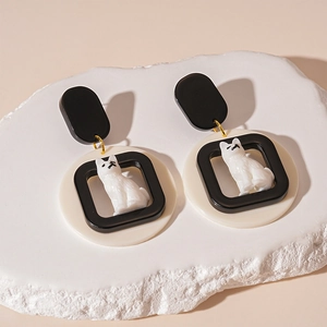 Close-up of cute acrylic cartoon puppy drop earrings with geometric black and white design
