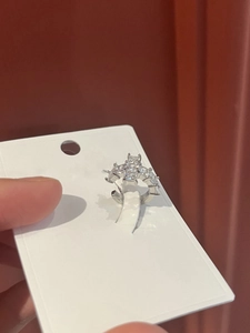 Detail of silver zircon cross ear cuff showing pavé-set stones on hand-held card