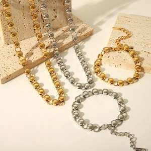 Detail of stainless steel ball bead jewelry set with gold and silver finishes on stone