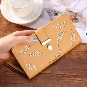 Detail of ginger yellow PU leather long wallet with laser-cut leaf patterns and metal charm