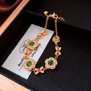 Detail of 24K gold plated bracelet with emerald cut gems and floral stone accents