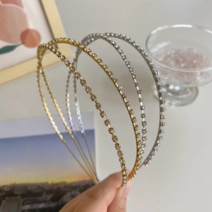 Detailed view of hand-held gold and silver alloy headbands with sparkling rhinestones