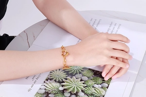 Close-up of a gold stainless steel heart chain bracelet with OT toggle clasp on a wrist