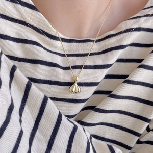 Close-up of a minimalist gold metal necklace with unique garlic bulb shaped pendant