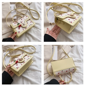 Detail of cream yellow handbag with cherry print, woven handle, and camellia metal lock