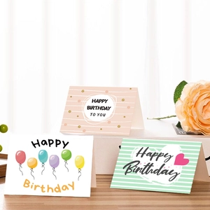 Trois cartes d'anniversaire assorties avec enveloppes sur une table en bois avec rose