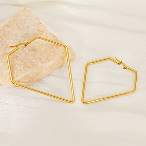 Minimalist gold geometric pentagon earrings set on textured stone and white fabric