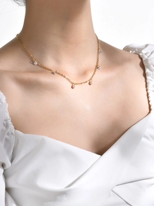 Close-up of a gold-plated 18K necklace with shimmering cubic zirconia pendants on a model