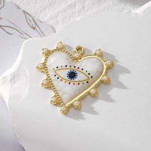 Golden heart pendant with evil eye pattern and pearl border on white textured stone