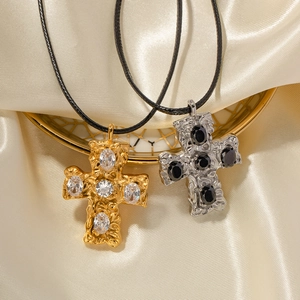 Détail de pendentifs croix martelés en or 18 carats et argent avec zircons sur soie