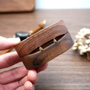Detailed view of closed oval black walnut jewelry box with high-quality gold metal hinge