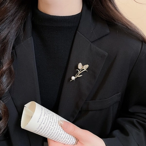 Detail of 14K gold plated tulip brooch with crystals and pearl on a black blazer