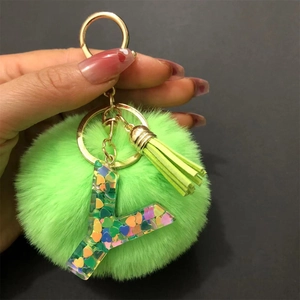 Detail of letter Y keychain with a green pompom, golden tassel, and heart sequins