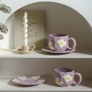 Detail of two irregular purple ceramic coffee cups with hand-painted white floral patterns