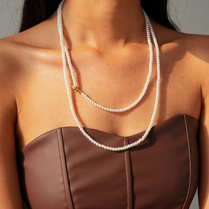 Detail of elegant double-layer pearl necklace with a gold OT toggle clasp on a female model