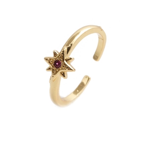 Detailed macro view of golden star-shaped ring with a vibrant pink gemstone center