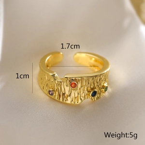 Detail of gold-plated geometric ring featuring a textured bark surface and colorful zircons