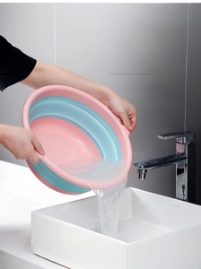 Detailed view of collapsible washbasin with side handles pouring water into a kitchen sink