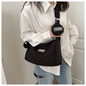 Détail du sac bandoulière en nylon noir avec mini pochette et breloque pelucheuse
