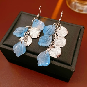 Détail de boucles d'oreilles en chaîne argentée avec perles de coquillage bleu clair