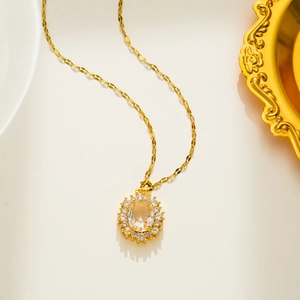 Detail of elegant gold necklace with oval clear crystal pendant and pavé rhinestones