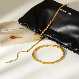 Bamboo-style 18k gold plated bangle and colorful crystal necklace on black texture