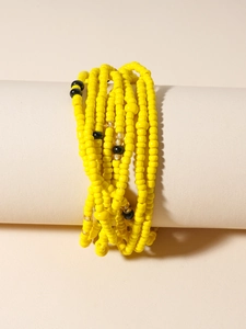 Detail of bohemian yellow beaded body chain with black accents on minimalist prop