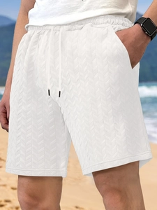 Detail of white men's shorts showing jacquard chevron texture and drawstring at the beach